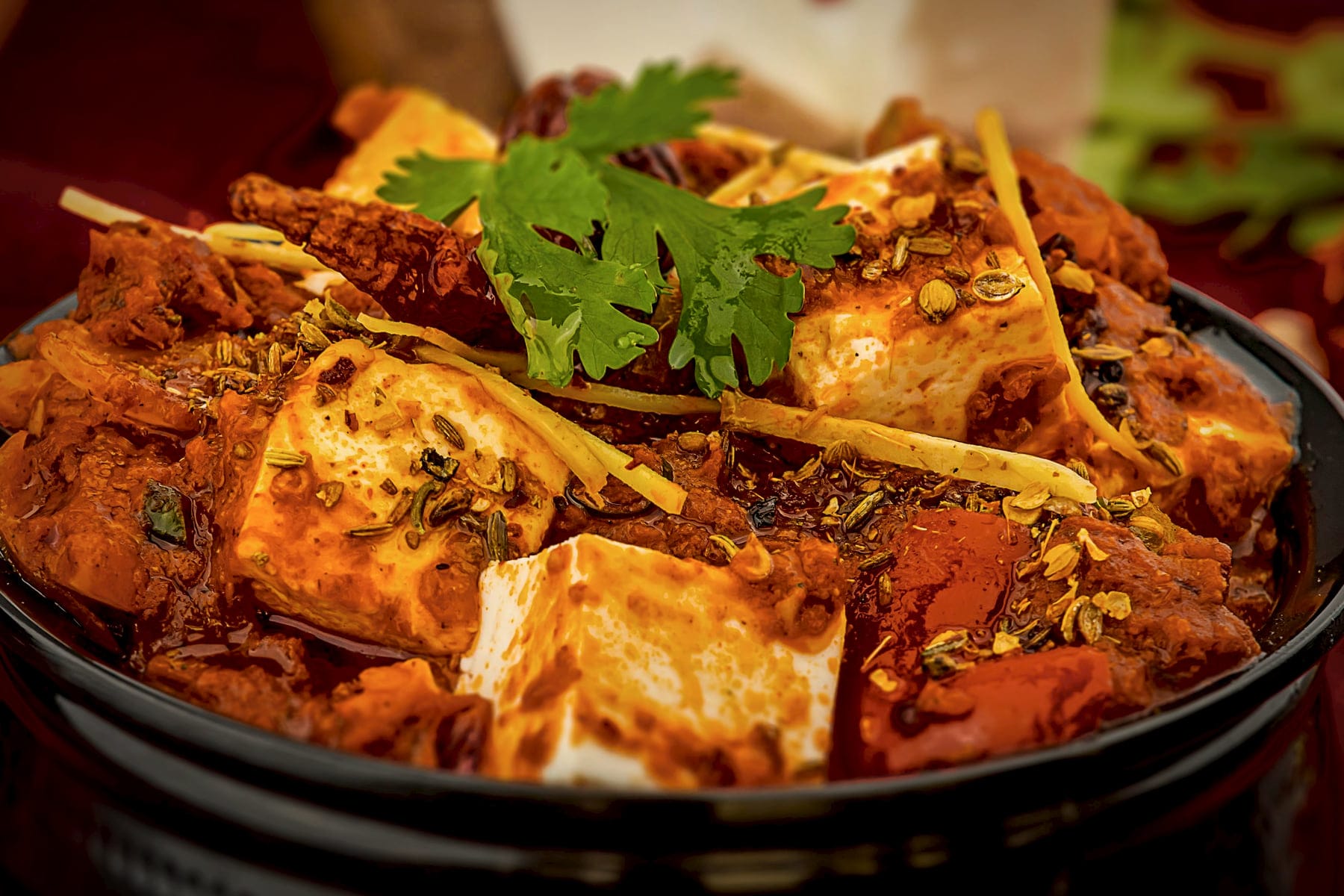 Paneer in a deep mahogany gravy in a dark hammered handi, finished with ginger julienne and coriander