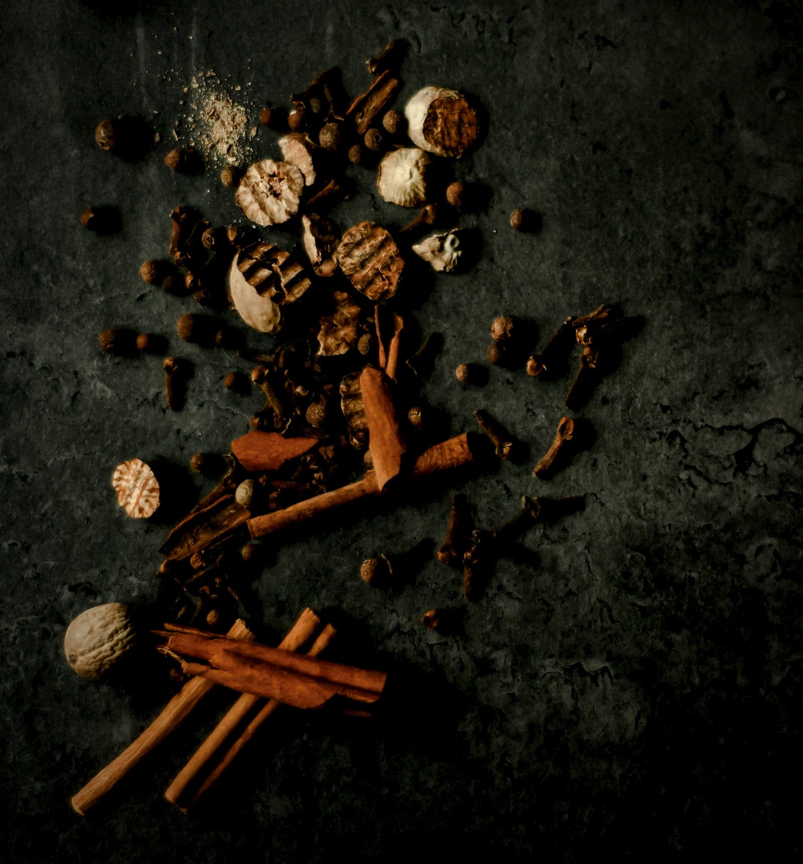 Whole spices scattered on dark stone